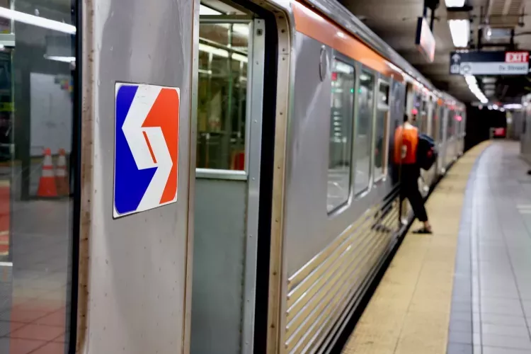 A SEPTA subway train at a Philadelphia station with a passenger boarding, featuring the iconic red, white, and blue SEPTA logo on the train exterior and platform signage in the background.